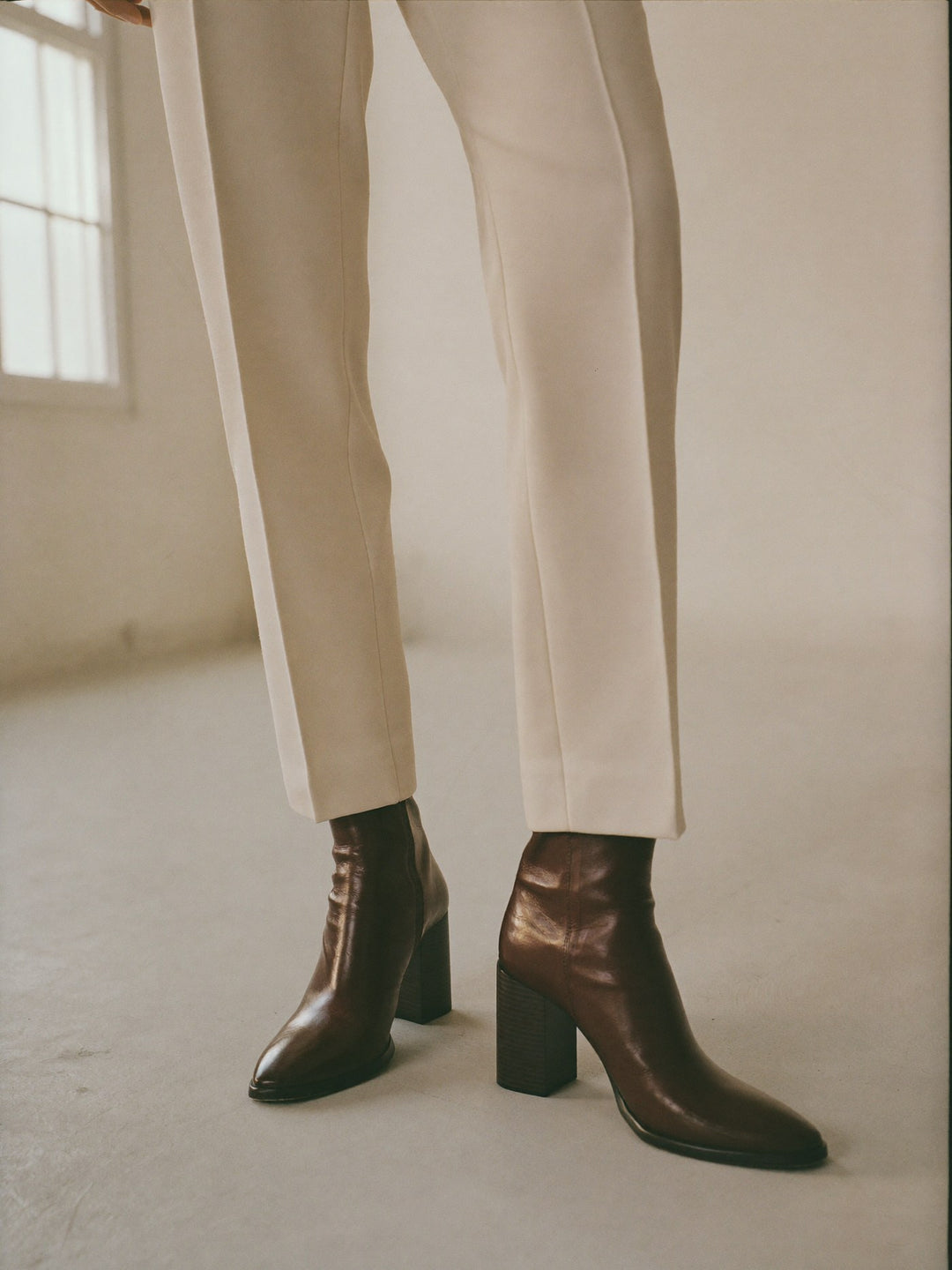Woman wearing dark brown leather ankle boots with cream tailored trousers
