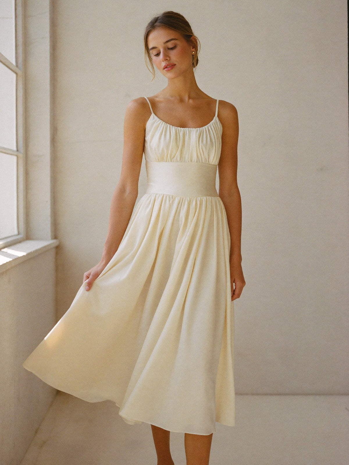 Woman in a flowing ivory midi dress in soft daylight