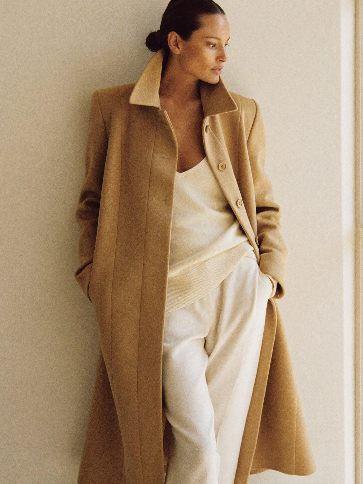 Woman in a tailored camel wool coat over a cream knit