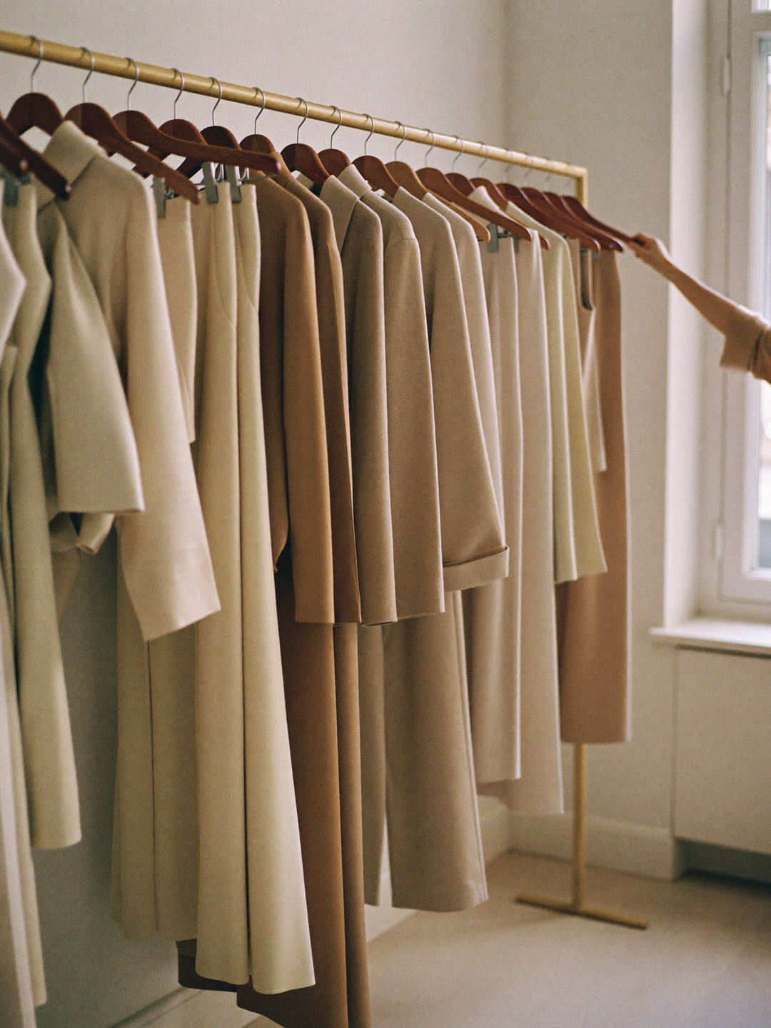 Rail of neutral womenswear in a minimal boutique