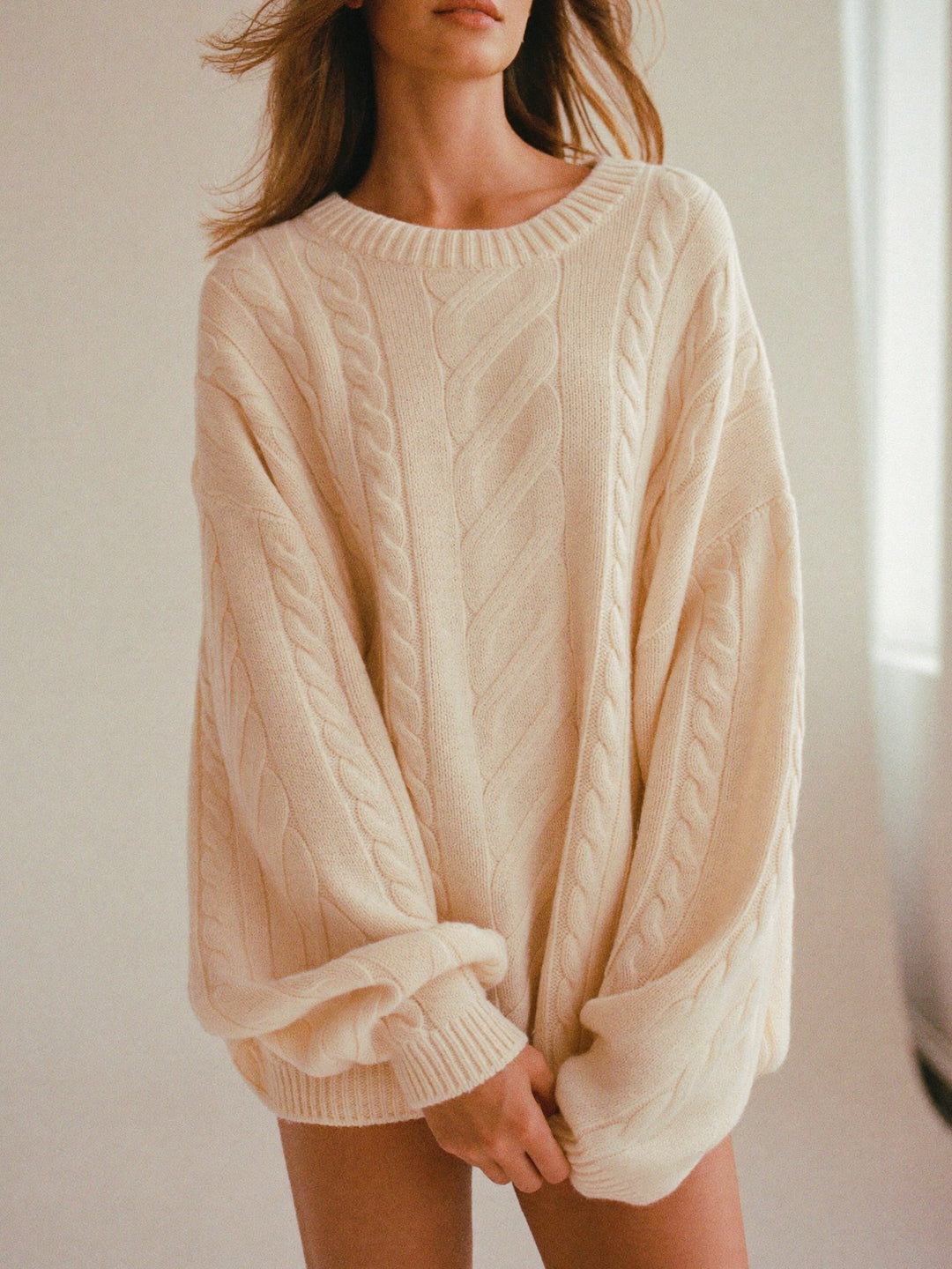 Woman in an oversized cream cable-knit sweater